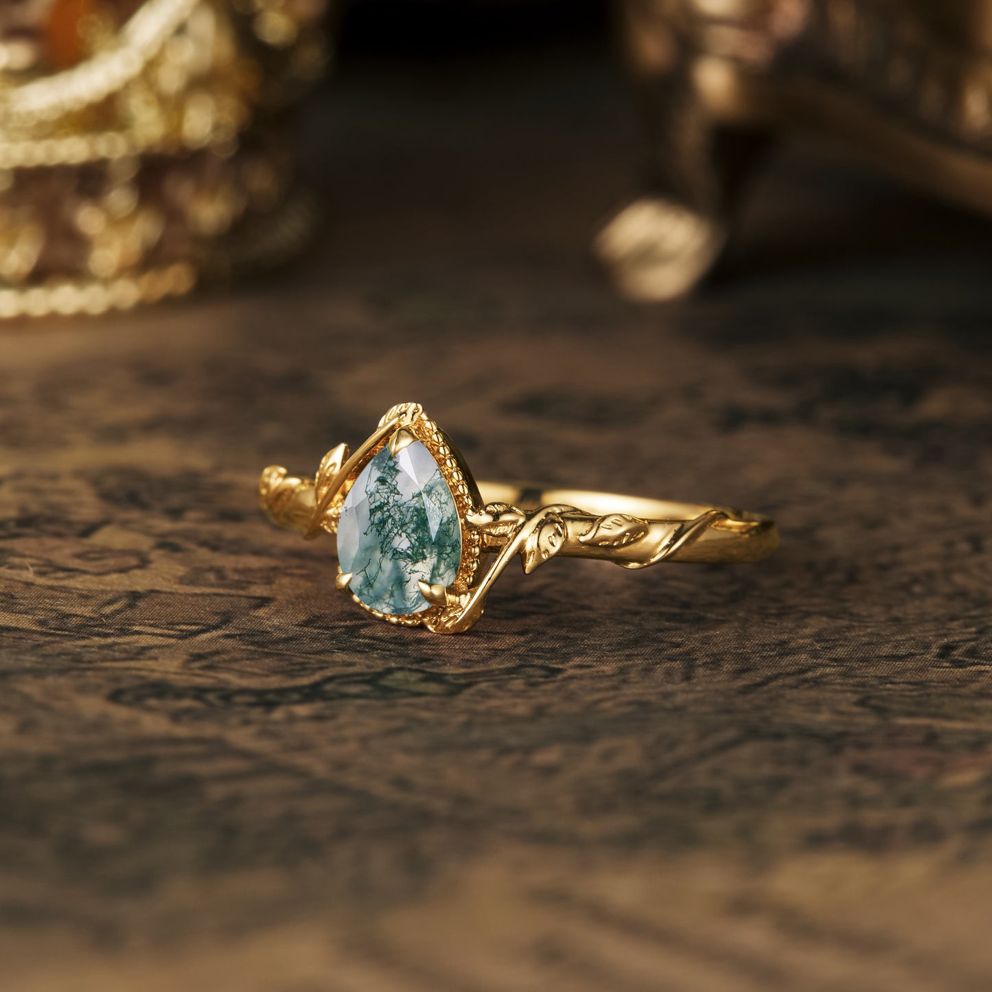 Elegant leaf-inspired gold engagement ring featuring pear-shaped moss agate