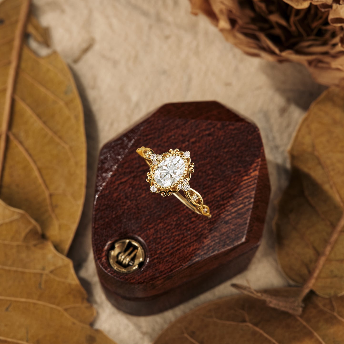 Elegant gold engagement ring with oval moissanite on a wooden display.