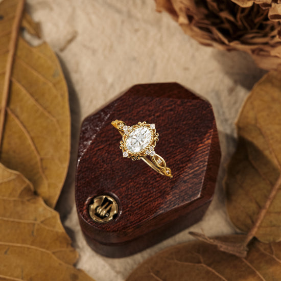 Elegant gold engagement ring with oval moissanite on a wooden display.