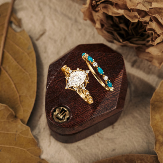 Gold engagement ring set featuring oval moissanite and turquoise accents on wooden display
