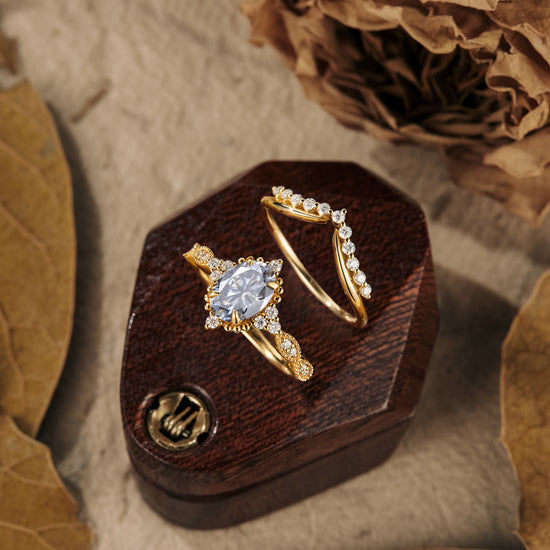 Unique gray moissanite engagement ring set with round accents on wooden display.