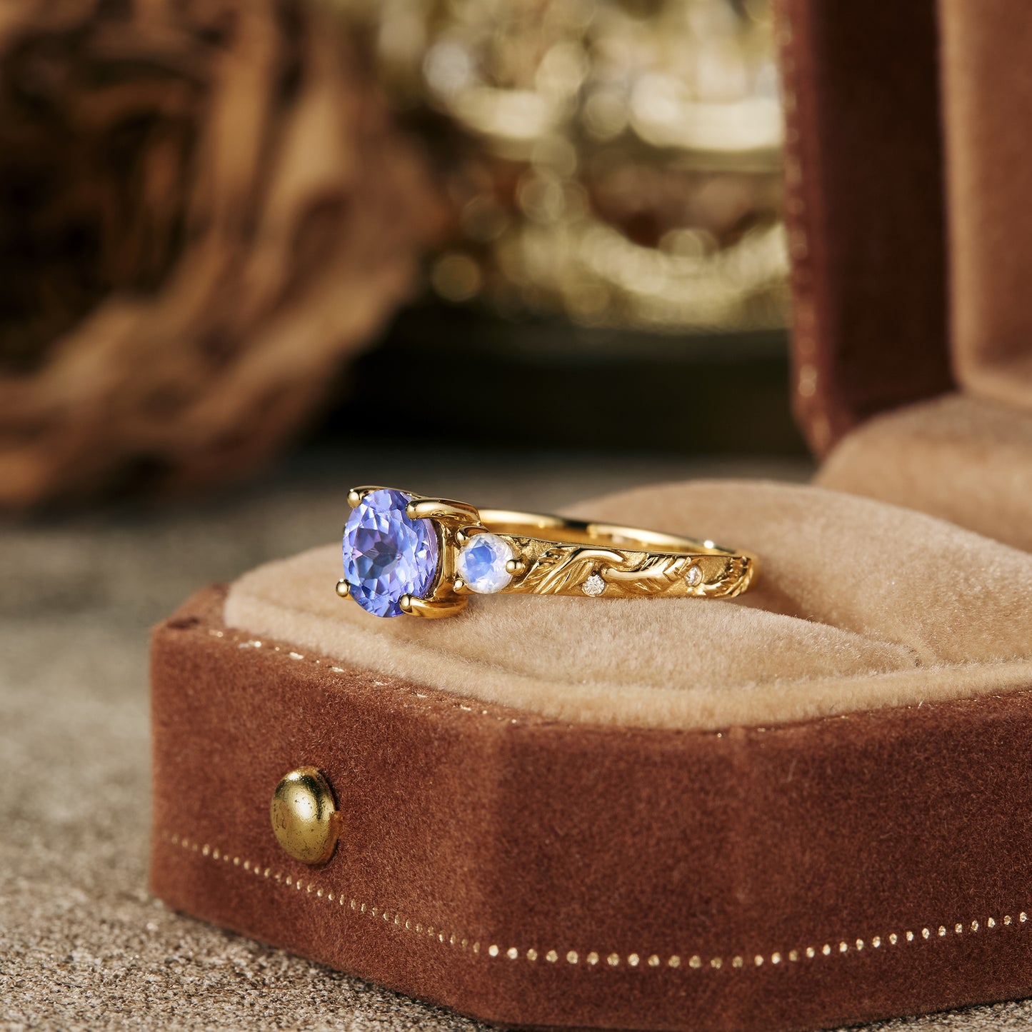 Tanzanite and moonstone engagement ring with leaf engraving on a velvet ring box