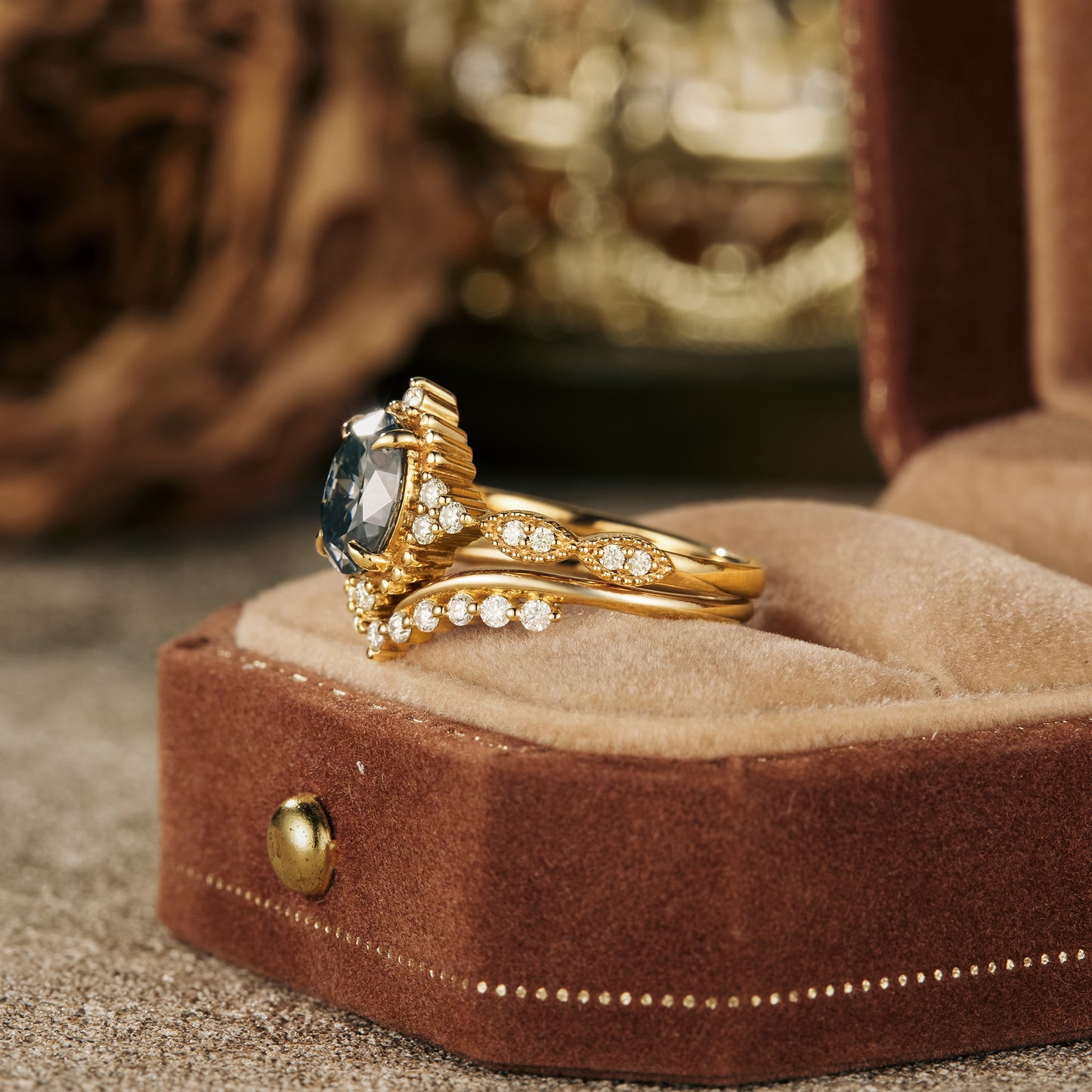 Nature-inspired gray moissanite engagement ring in gold setting displayed on velvet.