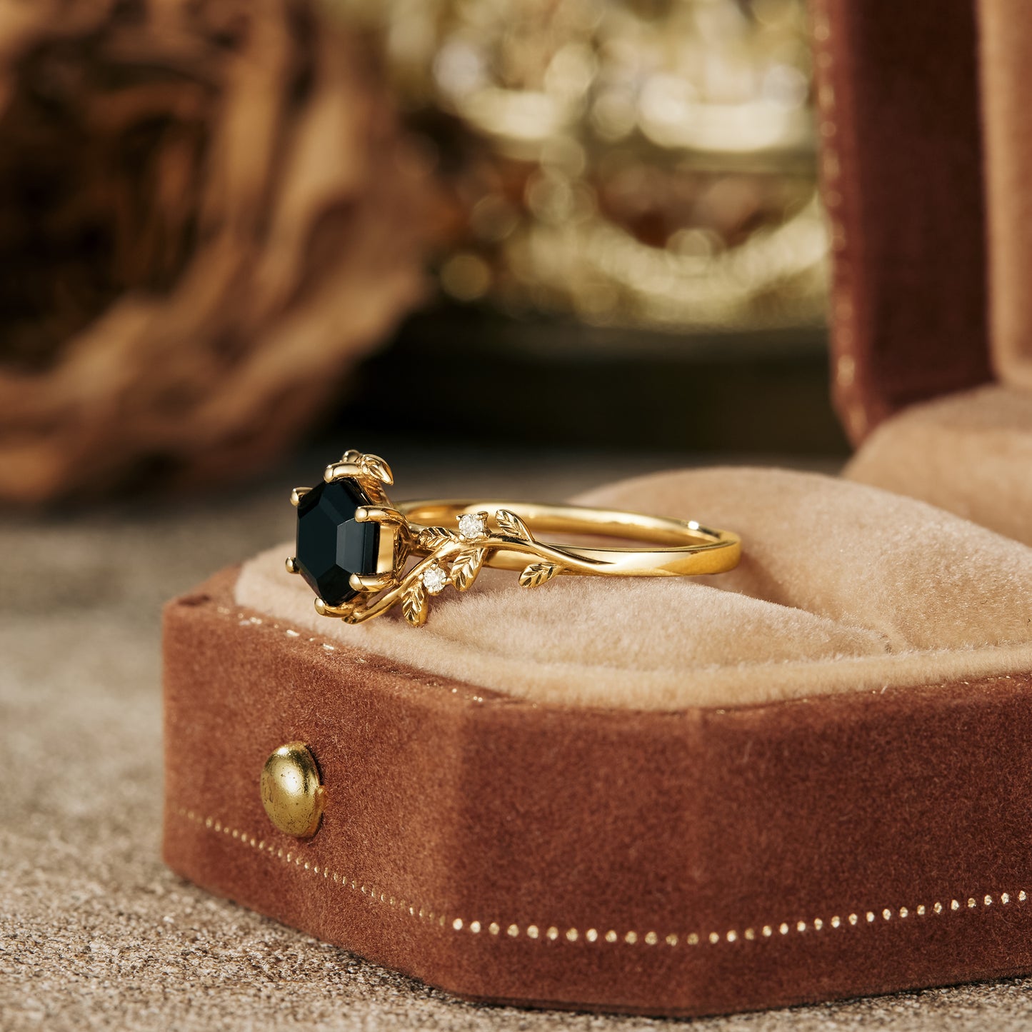 Gold leaf-inspired engagement ring with black onyx in a velvet box.