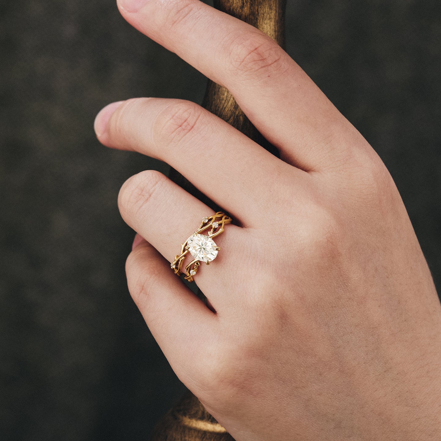 Hand wearing unique nature-inspired oval moissanite ring set in twisted gold.