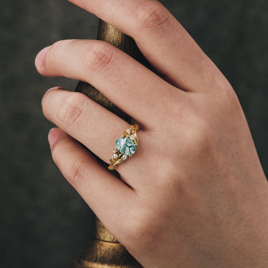 Vintage moss agate engagement ring with gold leaf and moissanite accents on hand