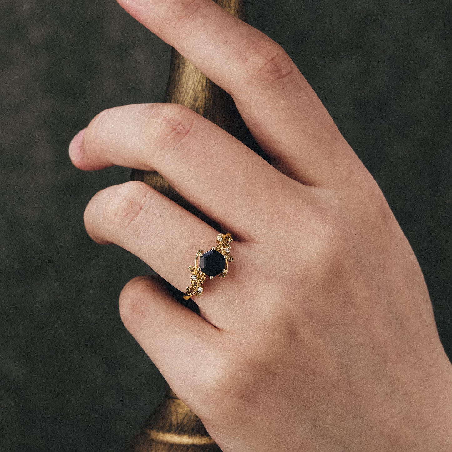 Mistletoe-inspired black onyx ring with leaf design displayed on a hand.