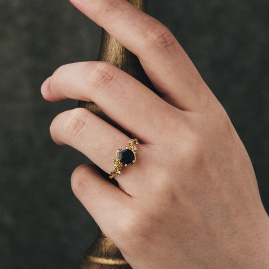 Mistletoe-inspired black onyx ring with leaf design displayed on a hand.