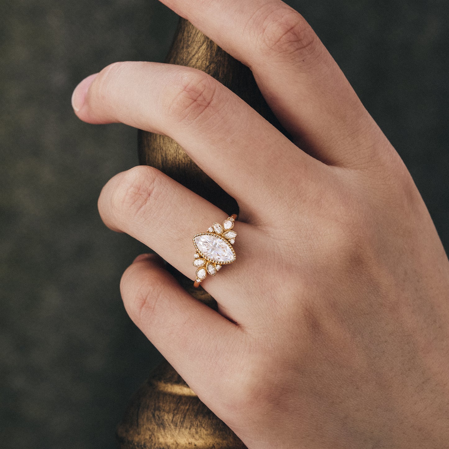 Vintage halo moissanite engagement ring with floral design worn on a hand.